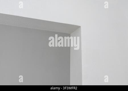 A close-up view of a clean architectural corner where two walls meet, showcasing a subtle contrast between gray and white surfaces Stock Photo