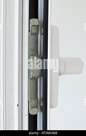 Detailed view of the internal components of a modern white window, showcasing the latch and handle assembly for secure closure Stock Photo