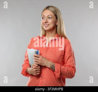 Teacher with notebooks and pen on light grey background Stock Photo