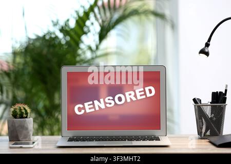 Censored content. Laptop displaying notification on desk Stock Photo