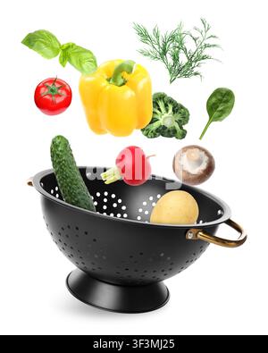 Vegetables and colander flying in air on white background Stock Photo