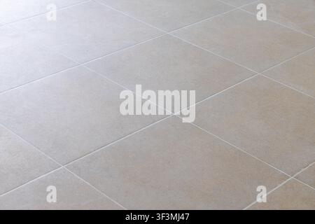 A close-up perspective of a clean, modern tiled floor with subtle texture and light reflecting off the surface Stock Photo