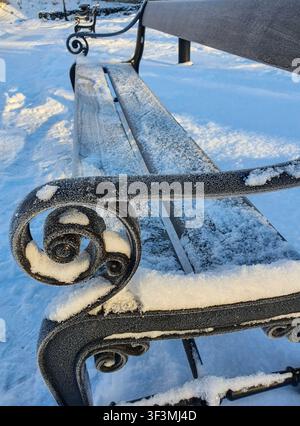 Close-up of a frosty park bench armrest covered in snow, Tallinn, Estonia. Stock Photo
