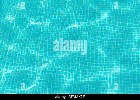 Clear turquoise water in a swimming pool with a tiled bottom and shimmering sunlight patterns creating a refreshing and serene atmosphere Stock Photo