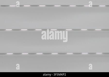 A detailed, abstract view of a silver roller blind showing its textured surface and repeating horizontal lines Stock Photo