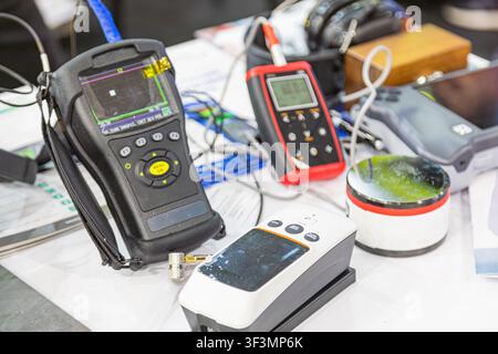 Technological testing instruments on table, variety of handheld devices for scientific measurements, screens and control panels visible, indoor labora Stock Photo