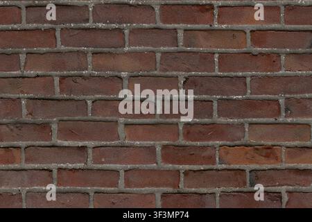 A high-detail industrial red brick wall with dark bricks and grey mortar in a standard bond pattern. Stock Photo