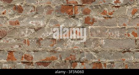 A close-up of a damaged red brick wall featuring exposed bricks and cracked, grey plaster patches. Stock Photo