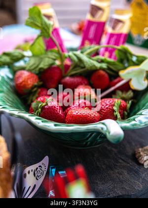 Fresh strawberries displayed in a decorative bowl at an outdoor food market. Stock Photo