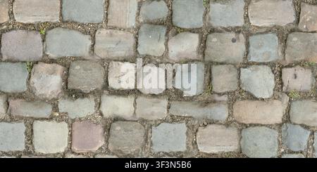 A colorful texture of rustic cobblestones in various shades of grey, tan, and brown. Stock Photo