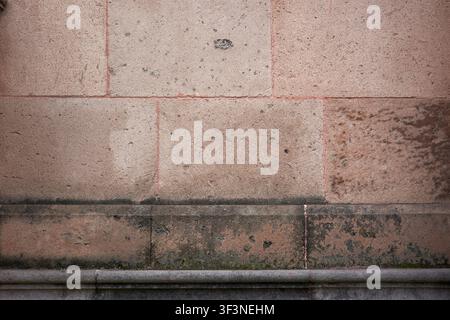 Horizontal old wall texture with large pink quarry blocks and weathered stone base Stock Photo