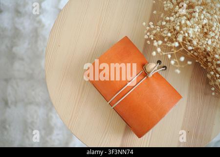 Leather notebook on a small wooden table with dried flowers Stock Photo