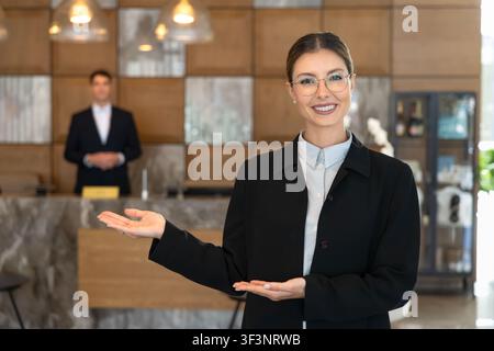 Female receptionist presenting hotel services at front desk Stock Photo