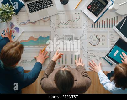 Dynamic business atmosphere as a diverse team collaborates around a table filled with AI-driven analytics, financial charts, and performance data visu Stock Photo