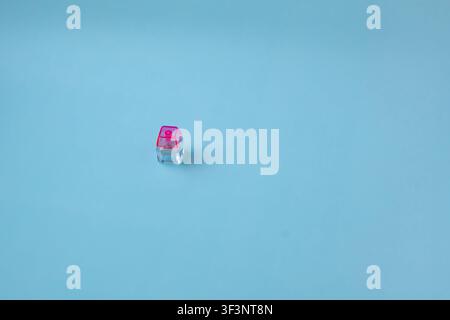 Single Transparent Mechanical Keyboard Switch with Pink Stem on Blue Background Stock Photo
