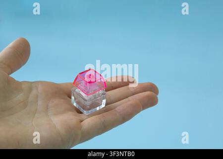 Transparent Mechanical Keyboard Switch with Pink Keycap Resting on Open Hand Stock Photo
