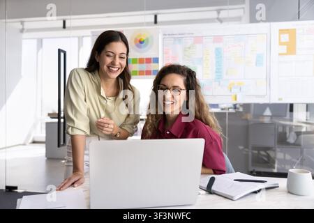 Designers working together at desk, focused on laptop screen Stock Photo