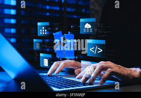 Low code no code development platform concept. Programmer using laptop, showing digital puzzle pieces connecting software modules, drag and drop app Stock Photo