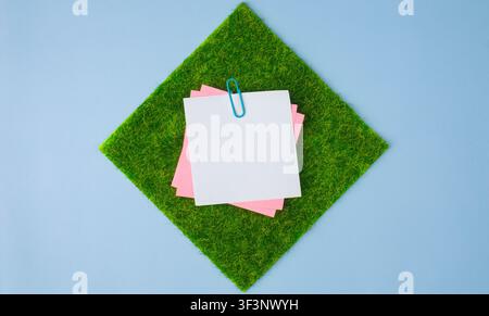 Sticky Notes on Square Grass Patch over Blue Background Stock Photo