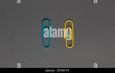 Blue and Yellow Paper Clips on Dark Desk Background Stock Photo