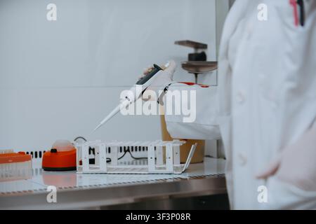 Scientist Using Pipette in Gloved Hand Conducting Laboratory Research With Sample Tray and Equipment Stock Photo