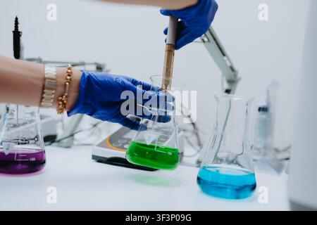 Scientist Wearing Gloves Conducting Chemical Experiment With Colorful Liquids In Laboratory Beakers Stock Photo