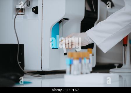 Lab Technician Loading Blood Sample Into Automated Analyzer in Clinical Laboratory Stock Photo