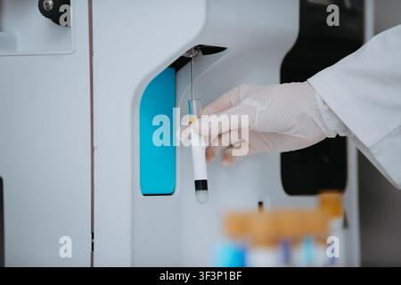 Medical Technician Holding Blood Test Tube Near Automated Laboratory Analyzer Machine For Diagnostic Testing Stock Photo