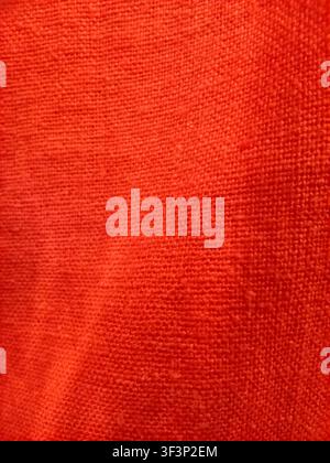 Macro detailed view of bright coral orange red knitted textile fabric showing fine yarn fibers and weave structure Stock Photo