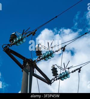 Glass insulators on a high-voltage power line against a blue sky Stock Photo