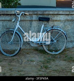 Vintage white bicycle leaning against a stone wall in northern Italy Stock Photo