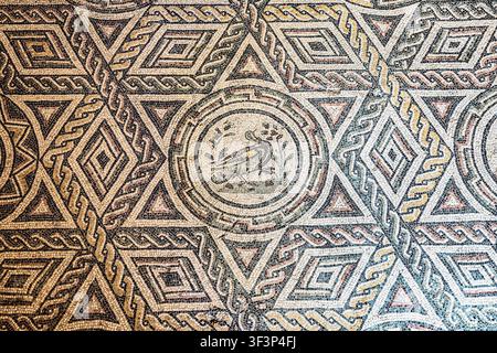 Ancient Roman floor mosaic showcasing intricate geometric patterns and a central bird, crafted for elegant decoration villa Romana del Casale, Piazza Stock Photo
