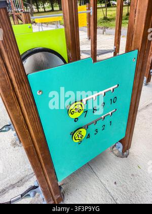 A close-up view of a bright turquoise panel on a wooden playground structure featuring a number game with sliding car icons Stock Photo