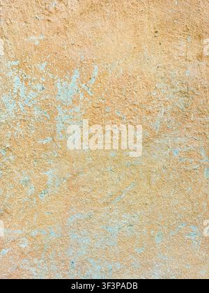 Close-up view of an old, textured wall surface showing layers of peeling paint and rough plaster, evoking a sense of history and tradition Stock Photo