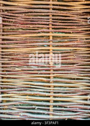Close-up view of a rustic, hand-woven fence made from natural branches, showcasing traditional rural construction techniques Stock Photo