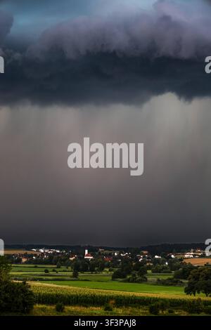 Bayern, Deutschland 18. 07. 2026: Im Bild: Gewitter in Bayern. Eine mächtige Gewitterzelle mit dichten Starkregenschauern zieht über die Ortschaft Aham im Landkreis Landshut. Dunkle Wolken und ein ausgeprägter Niederschlagsvorhang dominieren das Unwettergeschehen. Die Aufnahme eignet sich zur Illustration von Themen rund um Gewitter, Unwetter, Starkregen, Wetterwarnungen und extreme Wetterlagen. Bayern *** Bavaria, Germany, July 18, 2026. Pictured: Thunderstorm in Bavaria. A powerful thunderstorm cell with heavy downpours is moving over the village of Aham in the Landshut district. Dark clouds Stock Photo