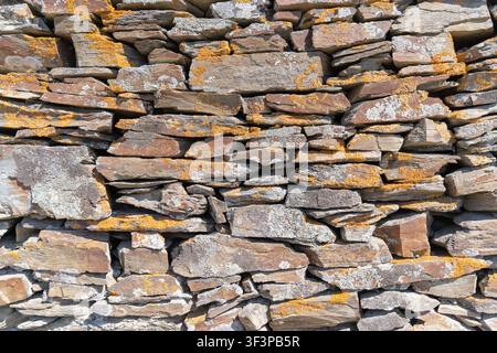 Close-up of a rustic dry stone wall with layered natural rocks creating a textured background Stock Photo