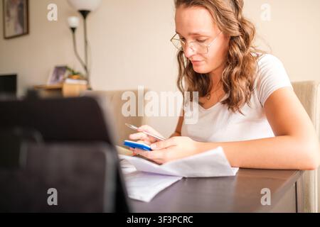 Woman calculating household expenses and planning budget at table Stock Photo