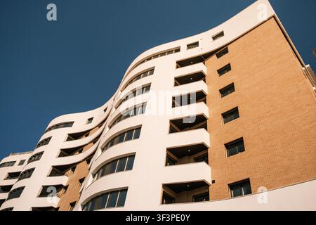 Modern building facade featuring curved architecture and brick cladding under a clear blue sky Stock Photo
