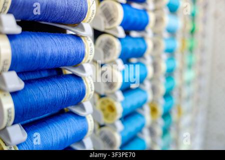 Rows of blue and turquoise sewing thread spools arranged on a retail rack Stock Photo