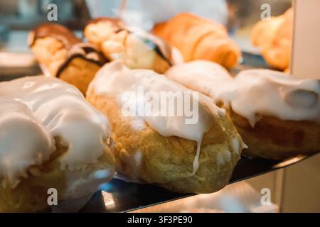 Freshly baked eclairs with vanilla and chocolate icing displayed in a bakery case Stock Photo