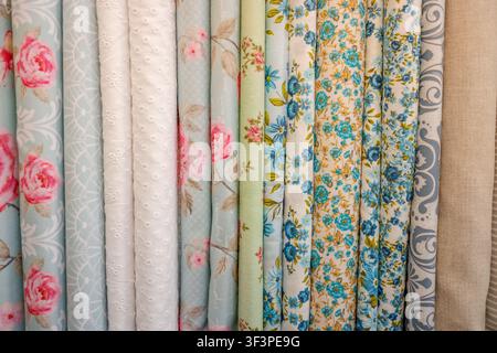Assortment of fabric rolls with colorful floral and patterned designs in pastel tones Stock Photo