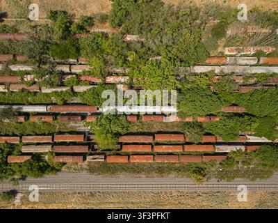 Aerial top down view of old rusty train wagons abandoned on overgrown tracks Stock Photo