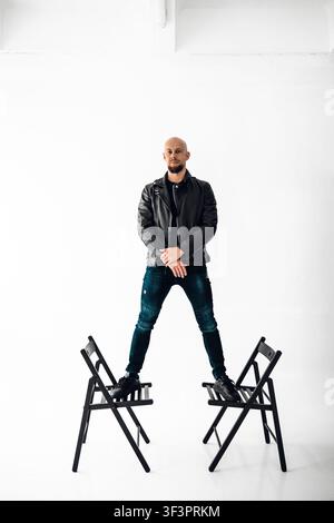 Man stands on two chairs in a studio with white background during a creative session Stock Photo