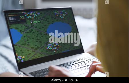 Woman playing economic strategy game on laptop. Stock Photo