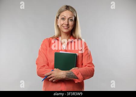 Teacher with notebooks and pen on light grey background Stock Photo