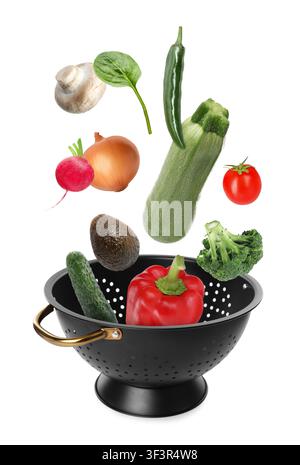 Different fresh vegetables falling into colander on white background Stock Photo