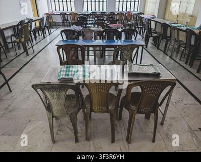 Empty dining hall with rows of plastic chairs and tables in a simple indoor canteen Stock Photo