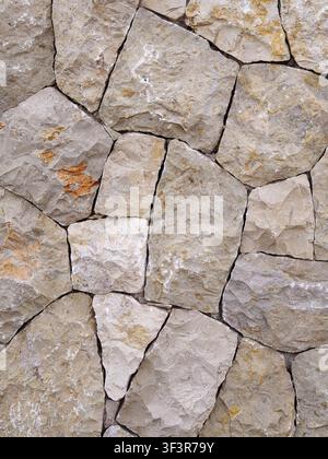 Rough rock wall showing uneven shapes and varied sizes of natural stones creating a rustic, durable, and decorative surface, suitable for architectura Stock Photo