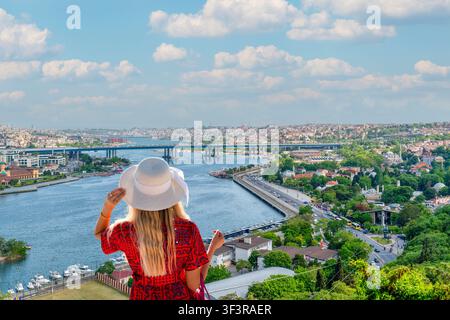 Back view of female tourist wearing sun hat looking at Golden Horn view from Pierre Loti Hill in İstanbul, Turkey Stock Photo